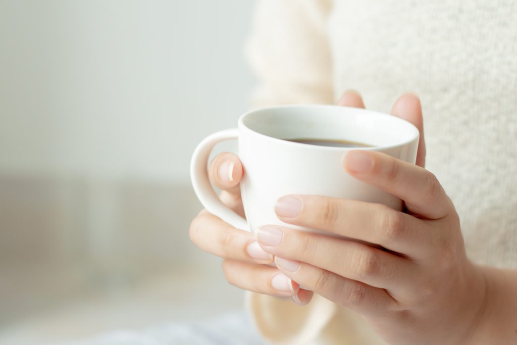Two hands holding a cup of tea.